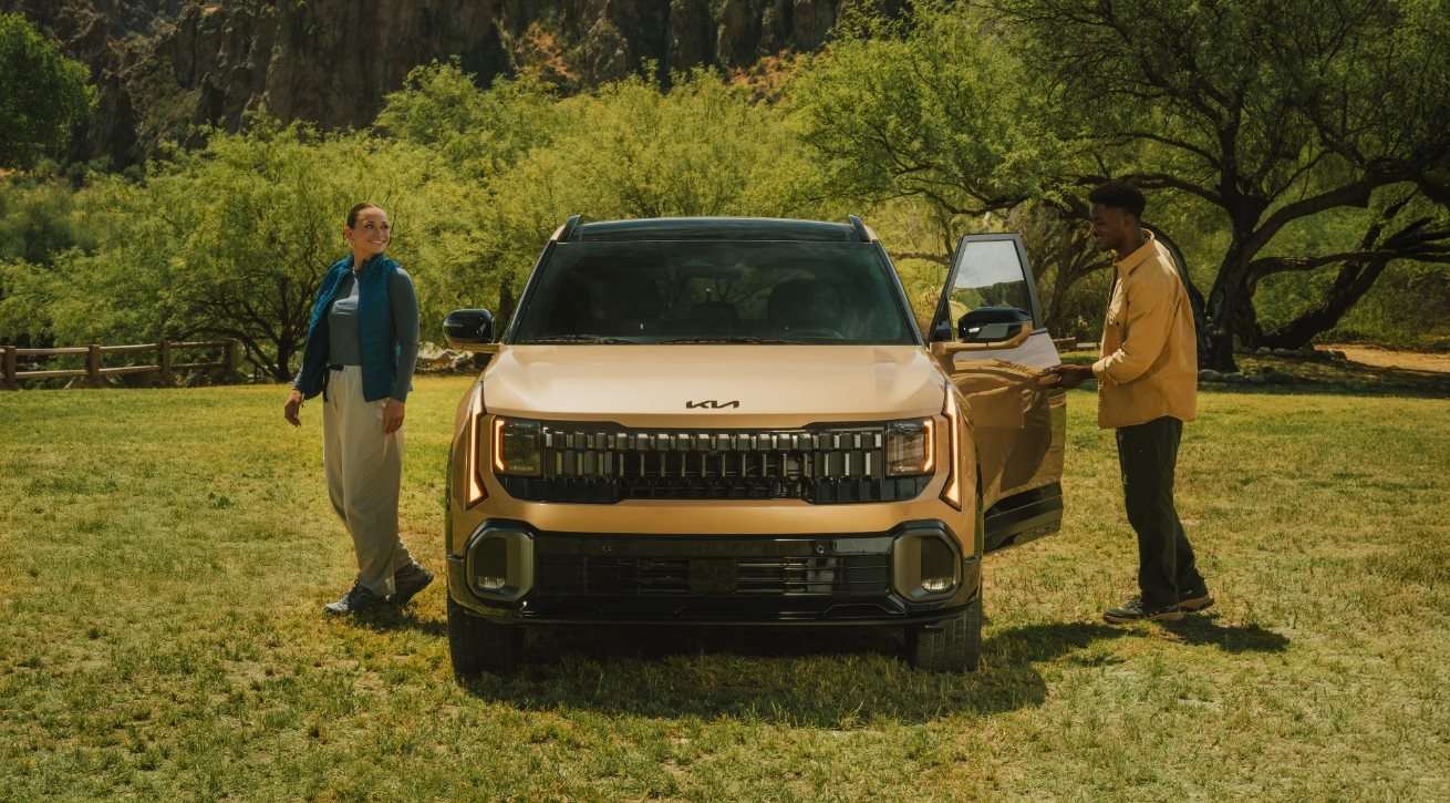 Kia Seltos front view on grass with two people standing beside it